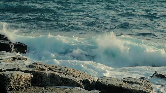 慢镜头中，海浪拍打在海滩上的岩石上，美极了。视频素材