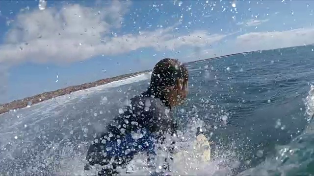 慢镜头特写:在阳光明媚的日子里，微笑的冲浪者冲浪破浪视频素材