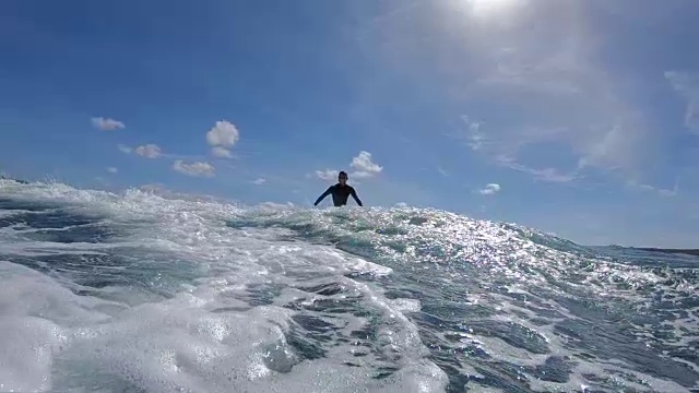 慢镜头，低角度:一个冲浪者雕刻一个波浪，把水溅到镜头上。视频素材