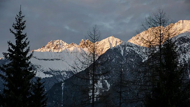 日落傍晚的颜色在雪山阿尔卑斯山脉时间流逝。在树上拍摄的多莉视频素材