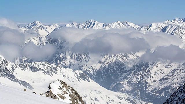 阳光明媚的一天在冬天的低云雪山山脉的时间流逝视频素材