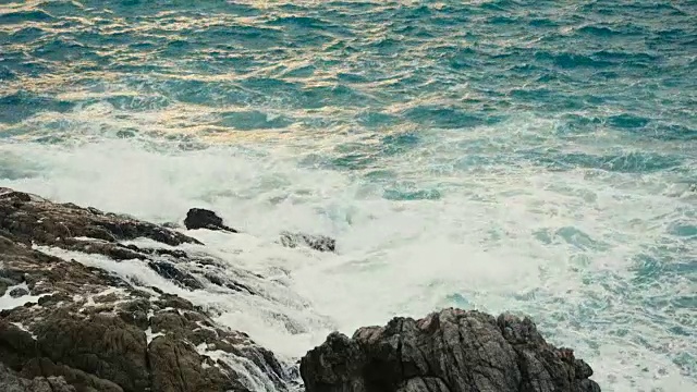 日落时海浪拍打着多岩石的海岸视频素材