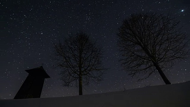 星星在夜空中移动，木制的钟楼和树木的剪影在冬天，天文时间流逝，摄影视频素材