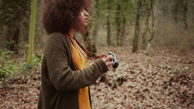 梳着非洲式发型的年轻女子在树林里拍照视频素材