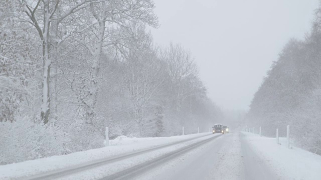 冬季驾驶-在一个多雾的日子里，大雪下的乡村道路上迎面而来的车辆视频素材