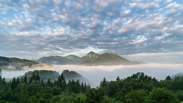 云移动在蓝色的天空和神奇的山景观在雾蒙蒙的早晨山谷时间流逝视频素材