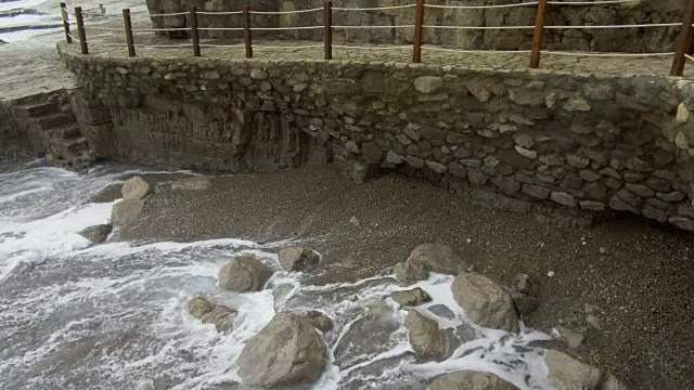 泡沫飞溅的海潮海浪冲刷着海沙海岸的石头视频素材