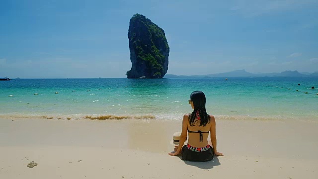 年轻的亚洲女子坐在美丽的海边休息。视频素材