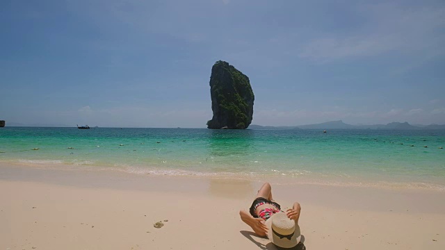 年轻的亚洲女子坐在美丽的海边休息。视频素材