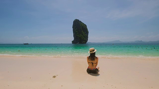 年轻的亚洲女子坐在美丽的海边休息。视频素材