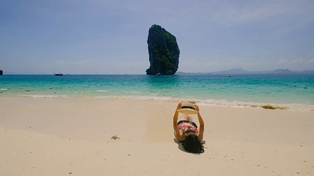 年轻的亚洲女子坐在美丽的海边休息。视频素材