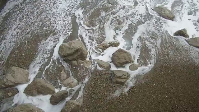 泡沫飞溅的海潮海浪冲刷着海沙海岸的石头视频素材