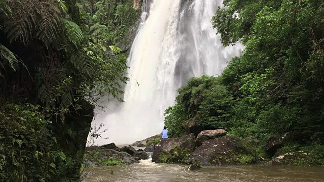 在巴西的一个森林地区，一名男子正在欣赏一个巨大的瀑布视频素材