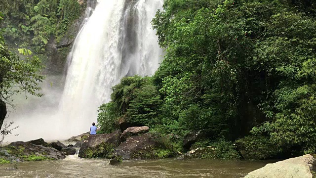 在巴西的一个森林地区，一名男子正在欣赏一个巨大的瀑布视频下载