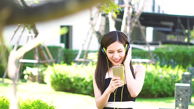 年轻的亚洲女子在花园里欣赏音乐视频素材