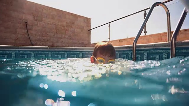 夏天戴着护目镜的小男孩在游泳池里游泳视频素材