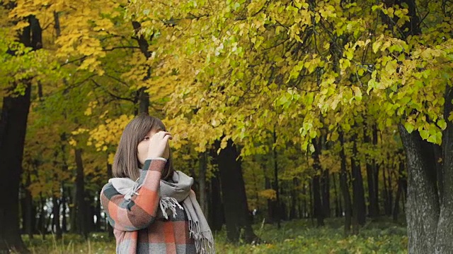 秋天的女孩在城市公园里散步。肖像快乐可爱和美丽的年轻女子在森林在秋天的颜色。视频素材