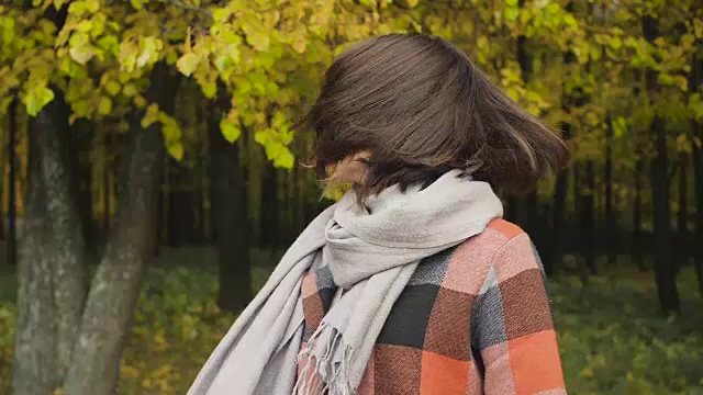 秋天的女孩在城市公园里散步。肖像快乐可爱和美丽的年轻女子在森林在秋天的颜色。视频素材