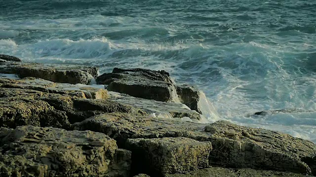 抽象的大海浪美丽的溅在海滩上的岩石在慢动作。视频素材