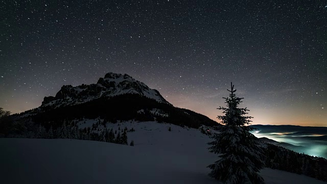 冬季天文时间流逝中，夜空中星星在山顶上移动视频素材