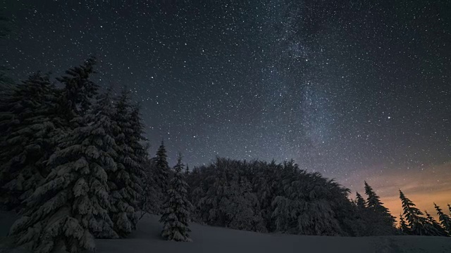 圣诞冬夜的景观与星星的天空移动在积雪的树。天文延时放大视频素材