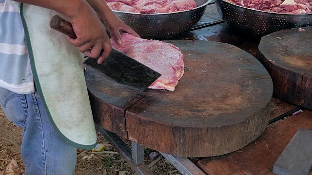 肉贩用切肉刀在圆形木砧板上切一块肉视频素材