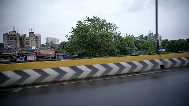 行驶在下雨的孟买公路上，俯瞰着贫穷的社区。视频素材