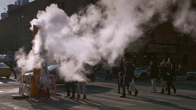 当行人在纽约街道上使用人行横道时，他们会穿过缕缕蒸汽。视频素材