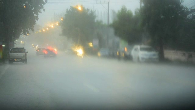 街上下雨，天气不好。路上和人行道上的水坑，雨点落在地上。汽车驶过路上的水坑。视频素材