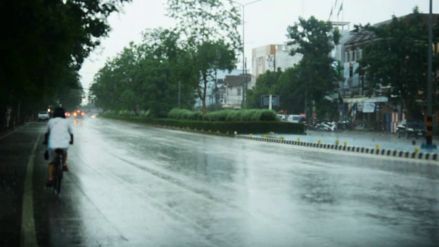 街上下雨，天气不好。路上和人行道上的水坑，雨点落在地上。汽车驶过路上的水坑。视频素材