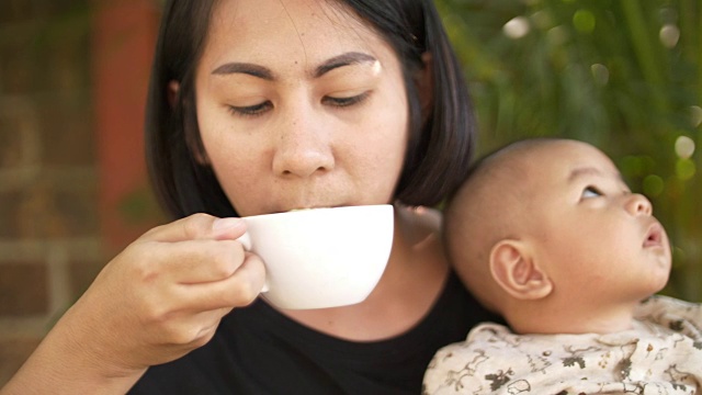 年轻的女人和孩子一起喝绿茶视频素材