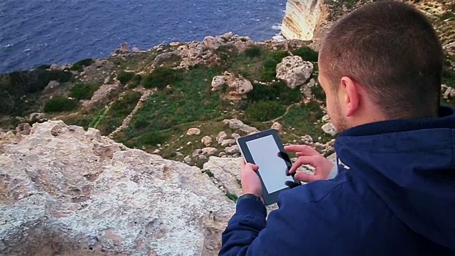 男子旅行者通过手机应用程序观看世界地图，同时在秋季旅行中在海边放松视频素材