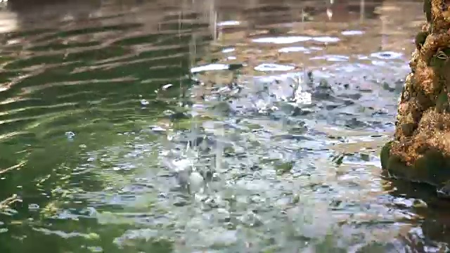 在石头喷水池里，水滴在水面上喷射视频素材