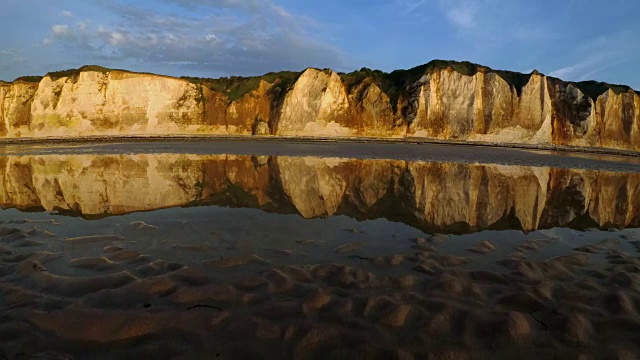 海岩反射在潮湿的沙滩上的英吉利海峡诺曼底，法国在日落退潮。如画的蓝天和白云。晚上静心、冥想、放松的概念视频素材