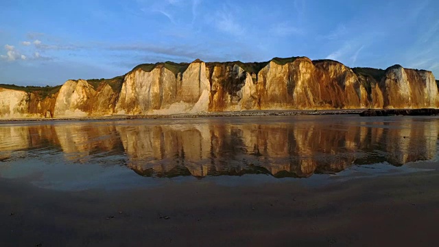 海岩反射在潮湿的沙滩上的英吉利海峡诺曼底，法国在日落退潮。如画的蓝天和白云。晚上静心、冥想、放松的概念视频素材