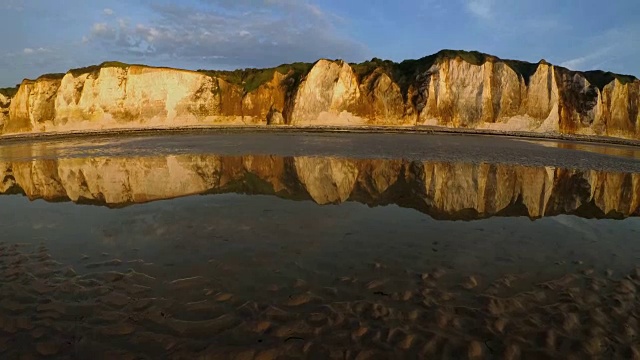 海岩反射在潮湿的沙滩上的英吉利海峡诺曼底，法国在日落退潮。如画的蓝天和白云。晚上静心、冥想、放松的概念视频素材