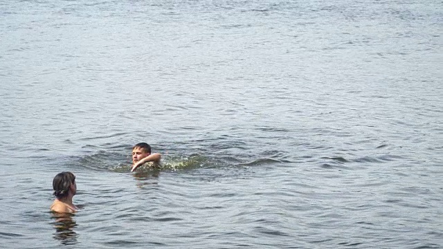 少年在他妈妈旁边的湖里游泳视频素材