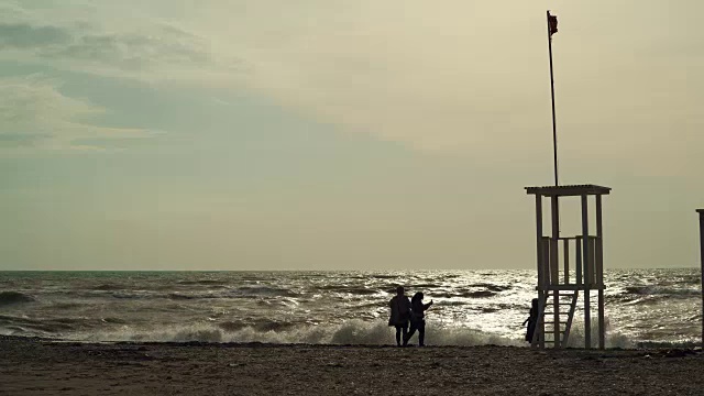 空荡荡的海滩上，人们的剪影在暴风雨的海面上视频素材