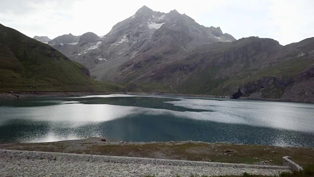 无人机飞过徒步者双臂张开，周围是风景优美的山湖景观视频素材