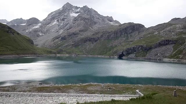 无人机飞过徒步者双臂张开，周围是风景优美的山湖景观视频素材