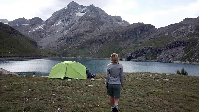 无人机飞过徒步者双臂张开，周围是风景优美的山湖景观视频素材