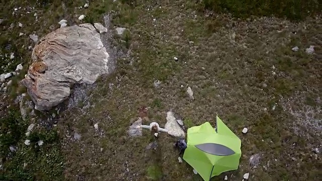 无人机飞过徒步者双臂张开，周围是风景优美的山湖景观视频素材