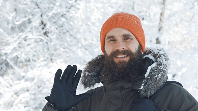 一名男子在一个冬日下雪天的户外对着镜头微笑和挥手视频素材