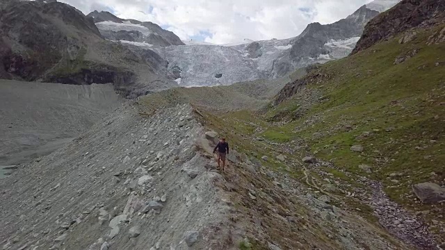 一名年轻男子在瑞士的山脊上徒步旅行的无人机镜头视频素材