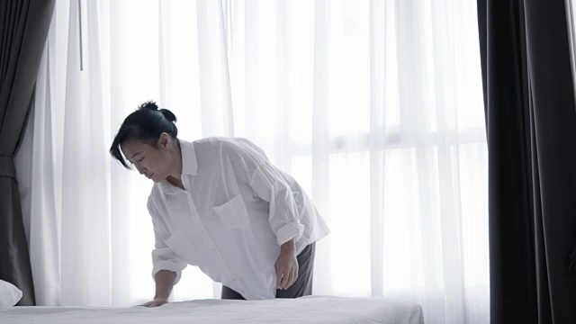 特写亚洲女人扔白色毯子在床上-股票视频视频素材