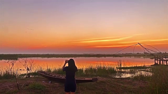 夕阳西下湖边垂钓的女人的后视图视频素材