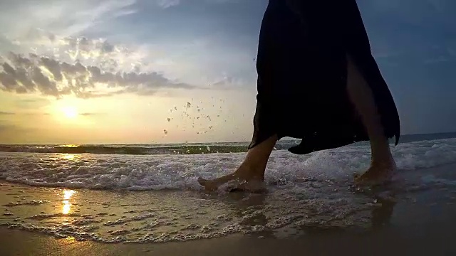 一名女子在沙滩上的海浪中行走的慢镜头视频素材