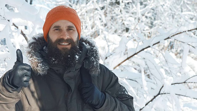 一名男子在一个冬日下雪天的户外对着镜头微笑和挥手视频素材