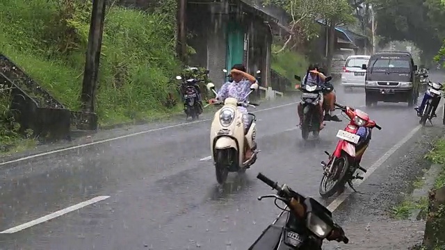 印度尼西亚巴厘岛乌布的一条典型街道上的交通在下雨的时候视频素材