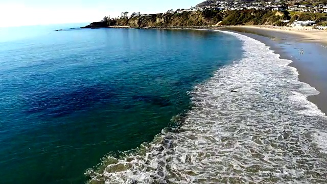 无人机拍摄飞到水晶清澈的海洋，从沙滩在盐溪海滩在拉古纳，加利福尼亚州。视频素材